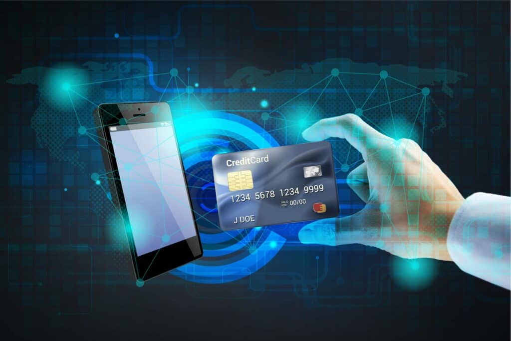 A hand holding a credit card near a smartphone