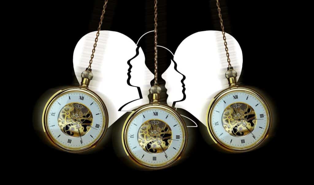 A pocket watch on a chain swinging in front of paper heads