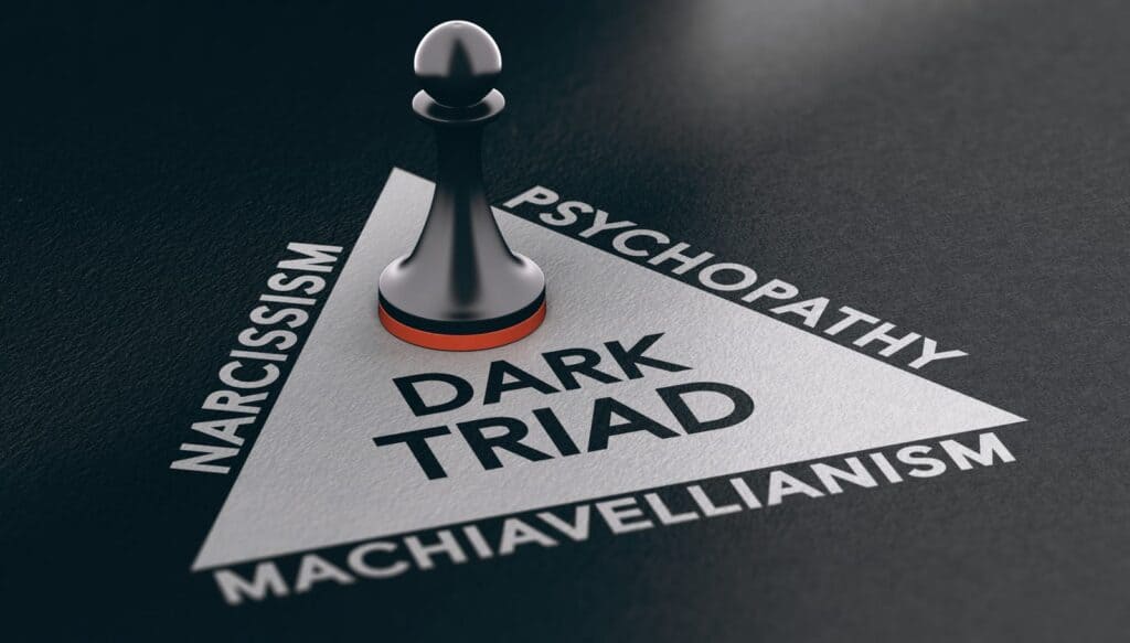 A dark chess pawn standing on a triangle labeled Dark Triad, with the words Narcissism, Psychopathy and Machiavellianism along its edges